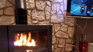 Un caminetto moderno con parete a muro in pietra e televisore montato.