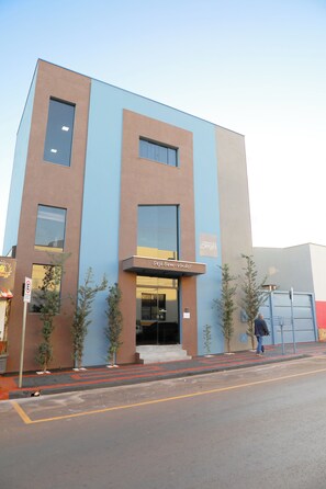 Un hôtel moderne à la façade bleue et marron, avec une entrée bien visible et une enseigne indiquant « Hôtel Georges ».