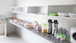 A kitchen area with a granite countertop, various food containers, a coffee machine, and a washing machine. - Hotel Borges (Quirinopolis)