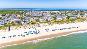 A coastal residential area with beachfront properties, a sandy beach, and a clear blue sky. - Oceanfront, Heated Pool, Elevator, Book today! (Corolla)