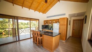 A spacious kitchen with a wooden island, large windows, and a view of the outdoors. - Vista del Campo Country Club & Villas (Jarabacoa)