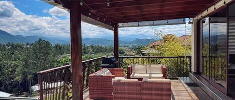 A pool area with a pergola, outdoor furniture, and a view of the mountains.