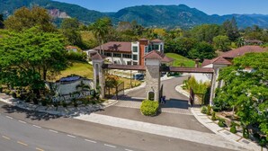 A hotel entrance with a stone archway, a sign for Vista Del Campo Restaurant, and a view of the surrounding greenery and mountains. - Vista del Campo Country Club & Villas (Jarabacoa)