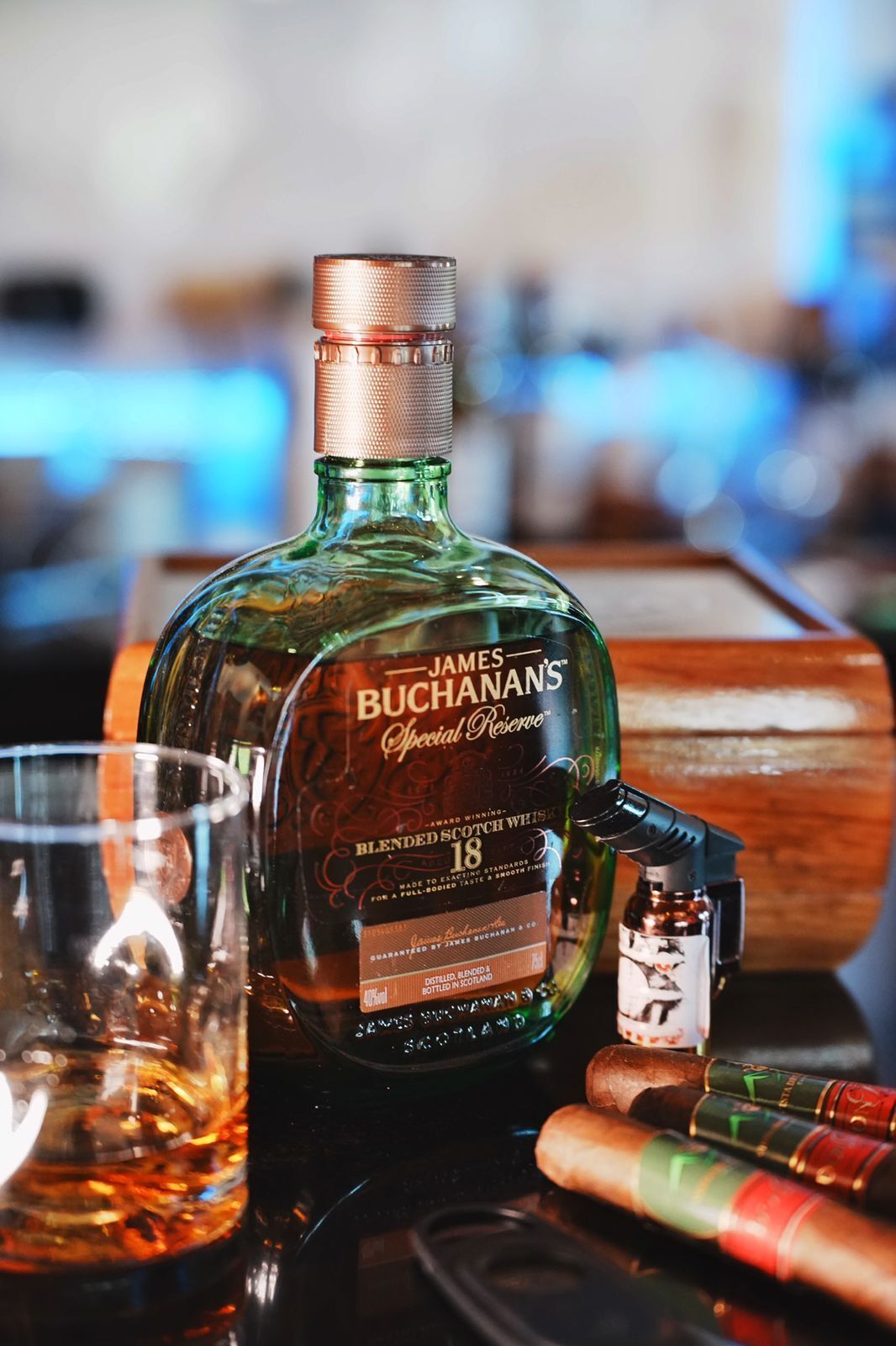 Una botella de whisky escocés Buchanan's Special Reserve, una copa y una caja de madera.