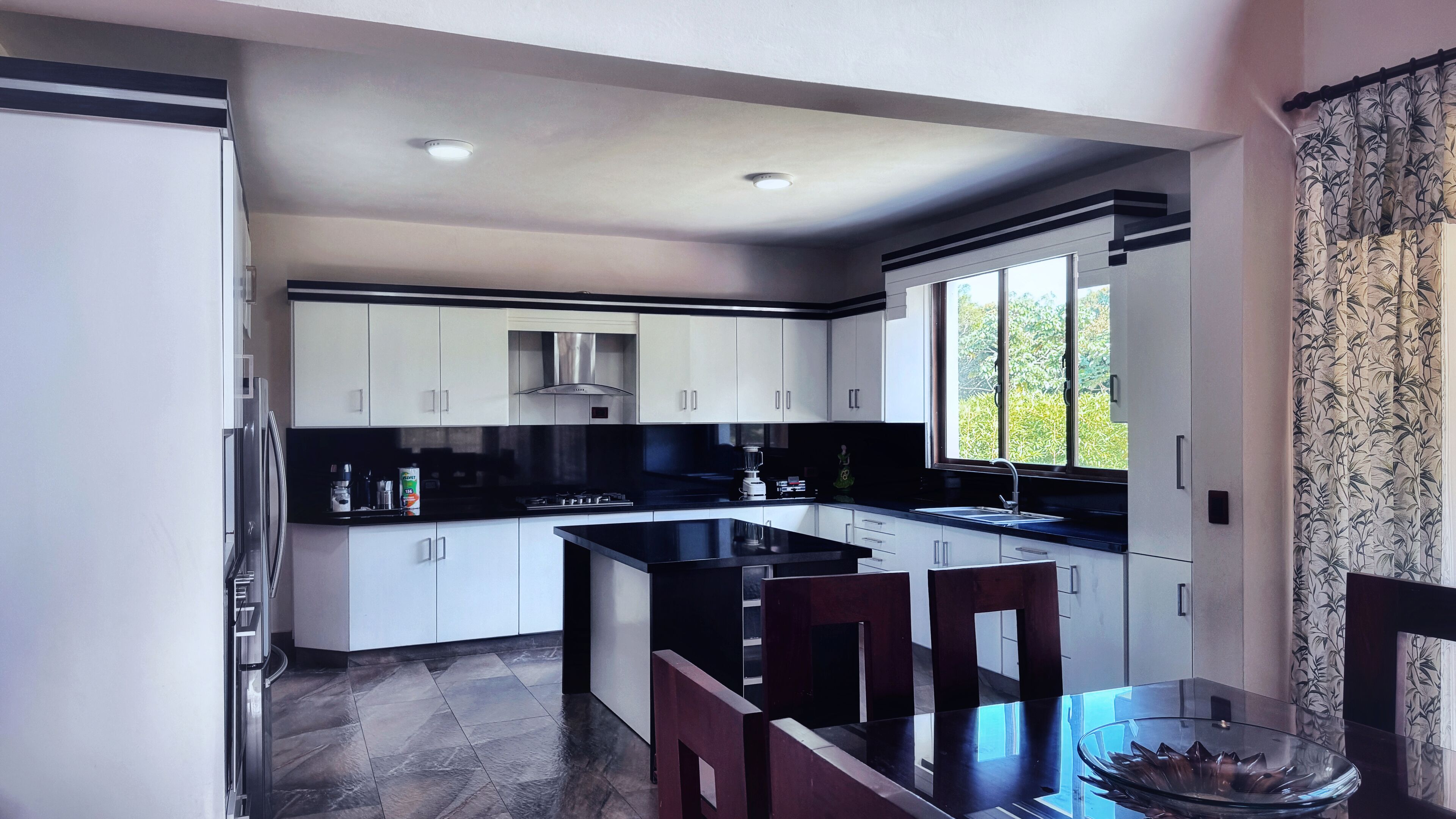 A modern kitchen with white cabinets, a black countertop, and a large window.