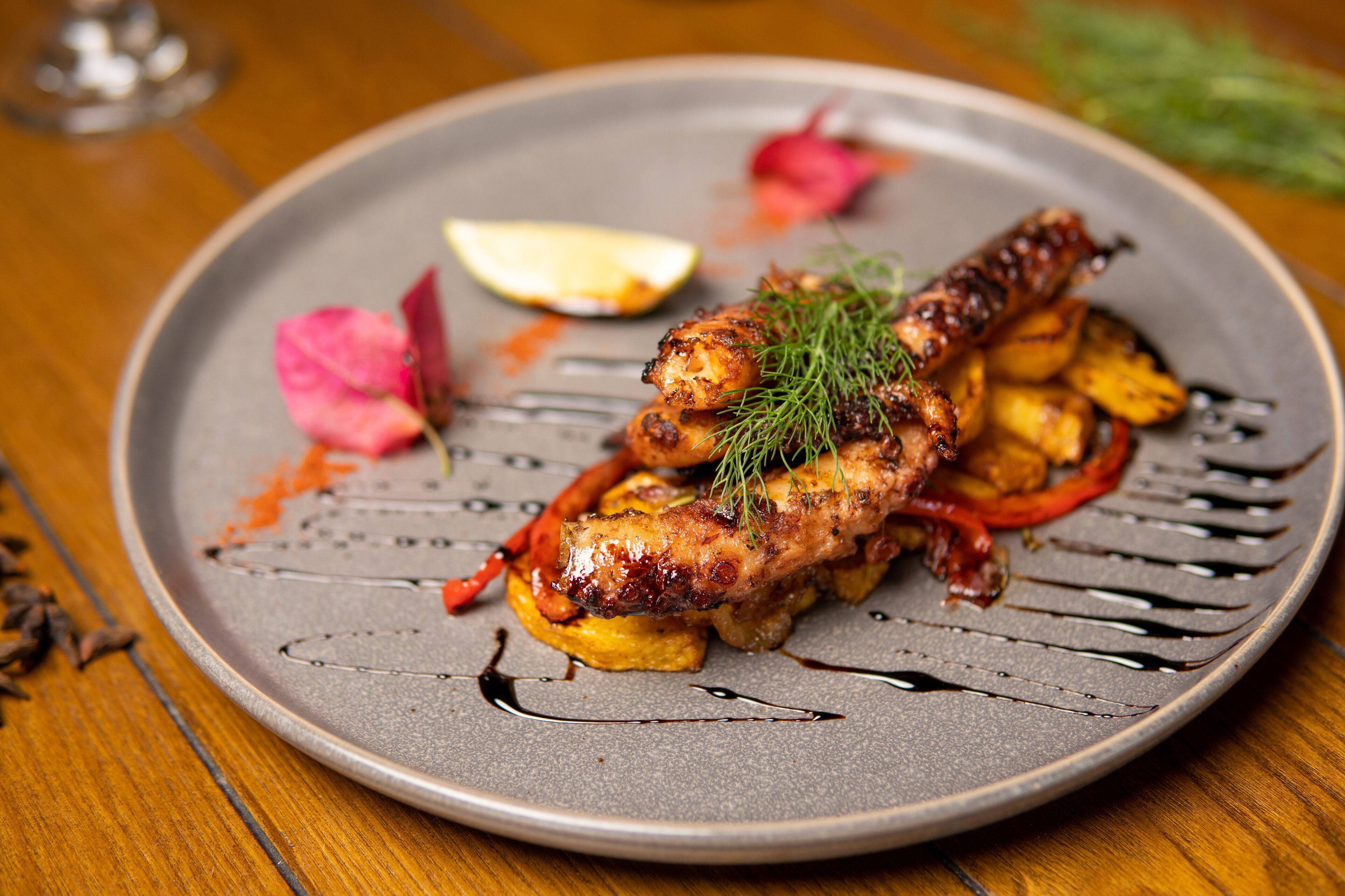 A plate of food with grilled meat, vegetables, and a garnish.