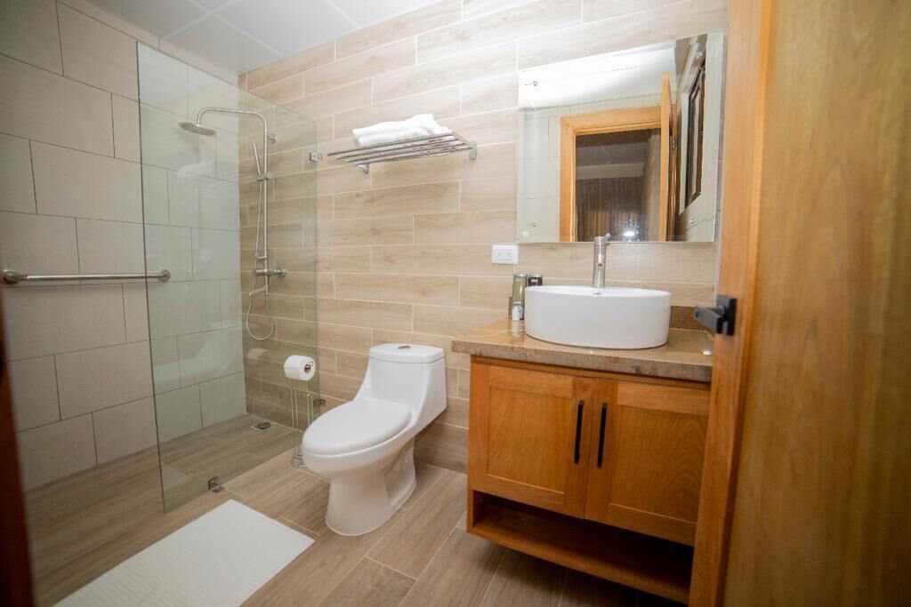 Un baño moderno con ducha acristalada, inodoro blanco y armarios de madera.