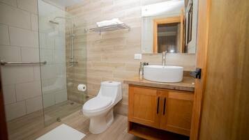 Un baño moderno con ducha acristalada, inodoro blanco y armarios de madera.