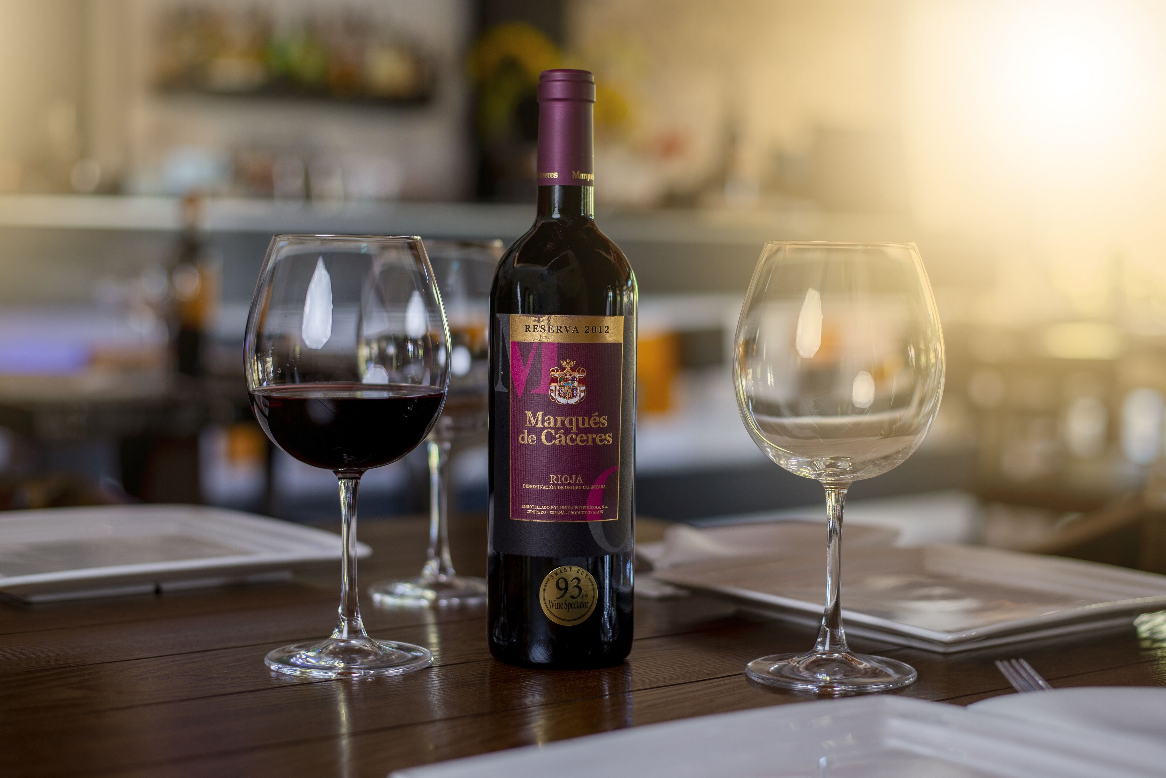 A bottle of wine and two glasses on a wooden table.