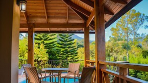 A wooden deck with a pool table and chairs, overlooking a lush garden and mountains. - Vista del Campo Country Club & Villas (Jarabacoa)