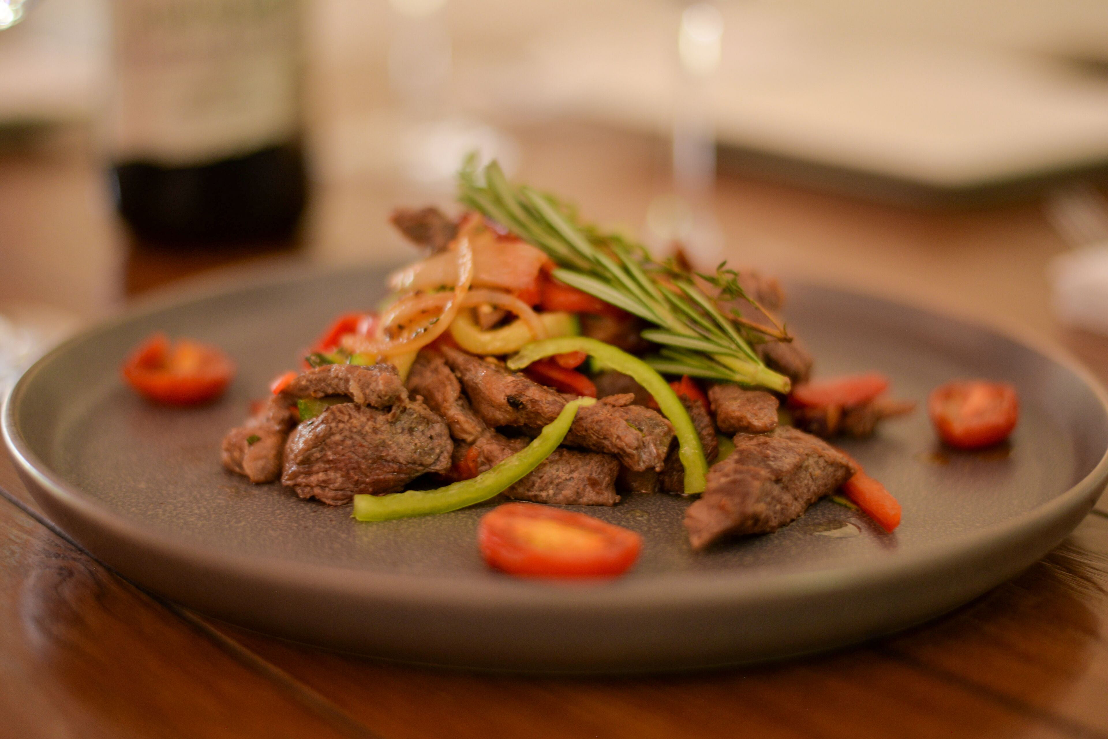 Une assiette de bœuf sauté aux légumes, présentée sur une assiette foncée.