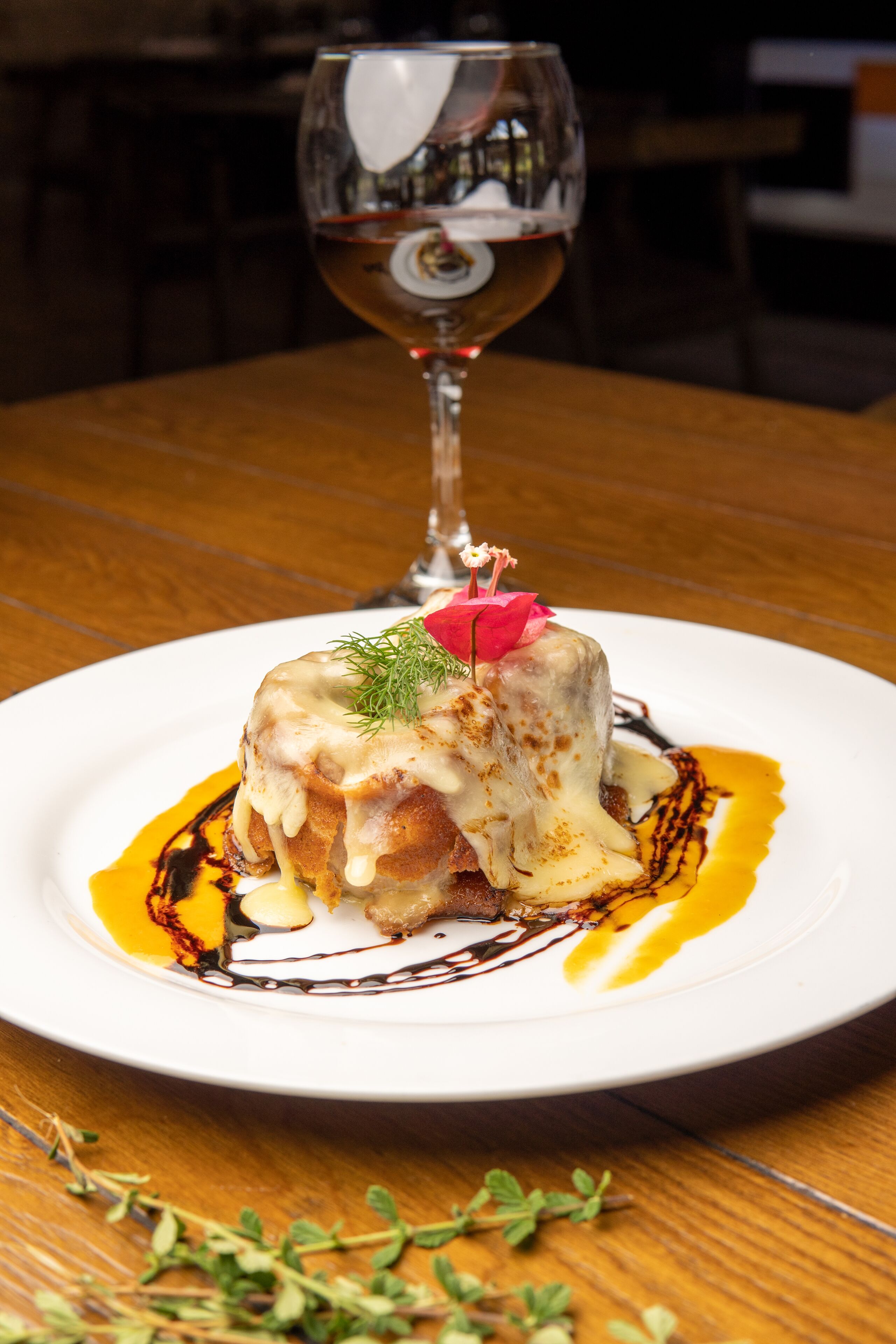 Un postre sobre un plato blanco, con una copa de vino blanco al fondo.