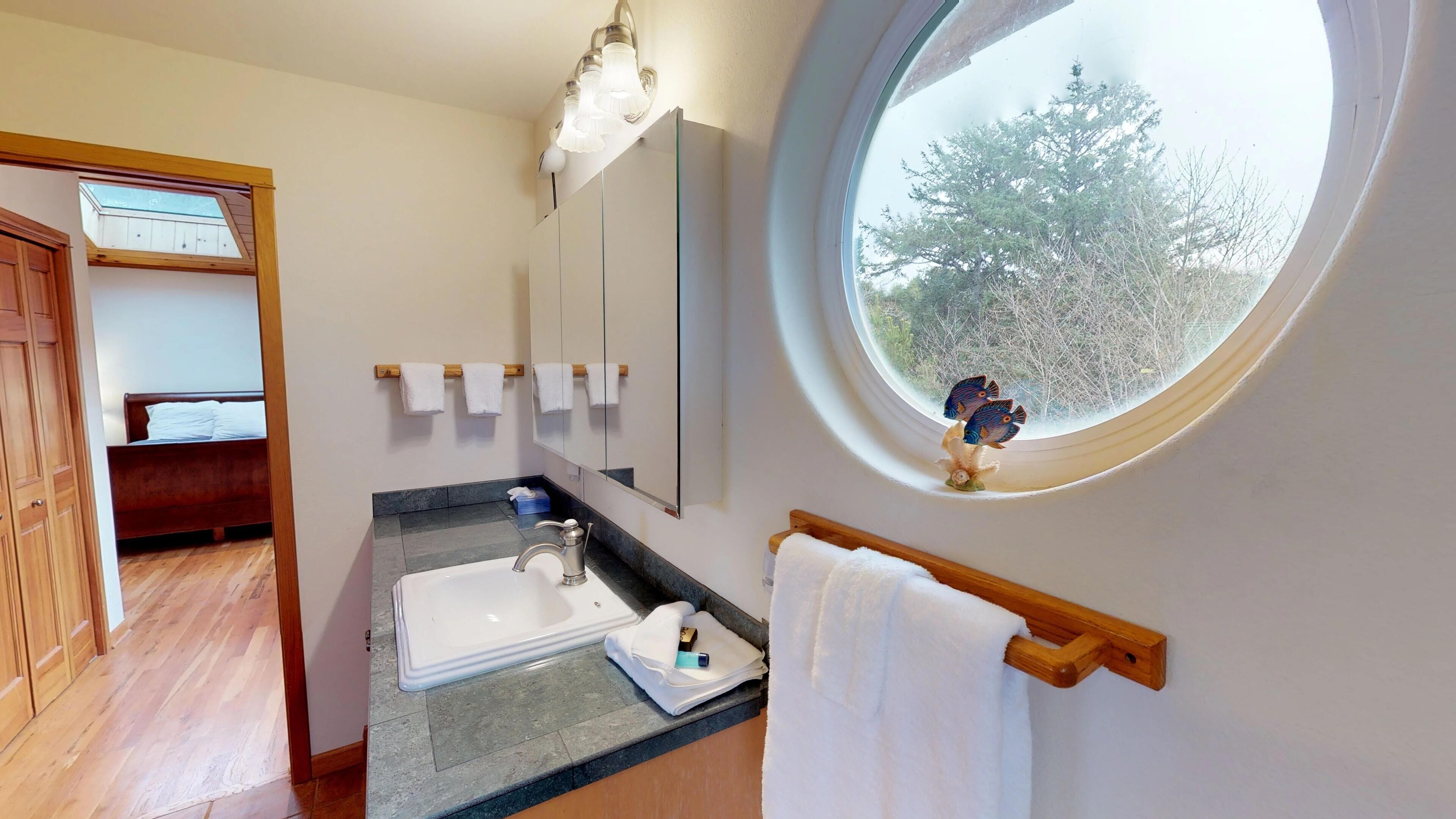 A bathroom with a skylight, a large mirror, a sink, and a wooden bench.