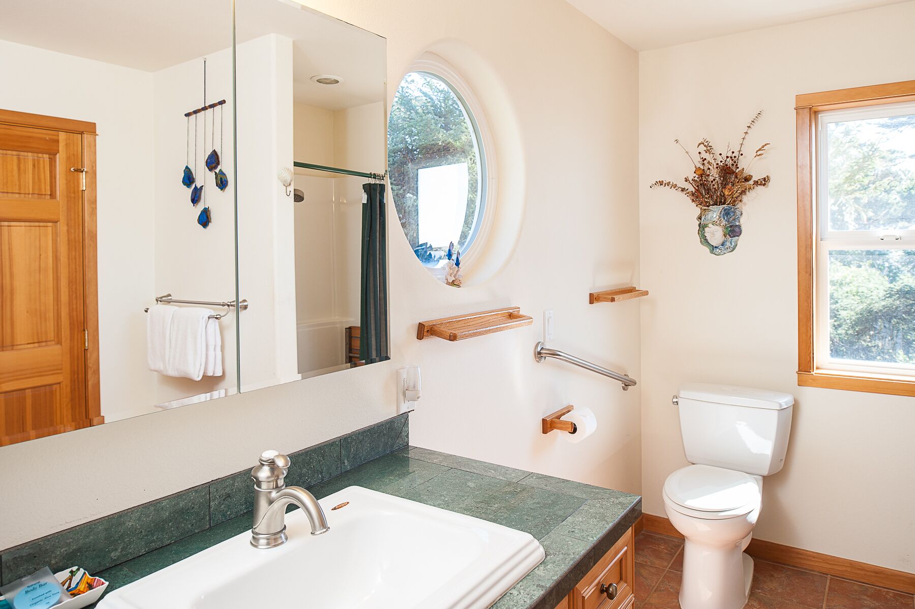 A bathroom with a white sink, a toilet, a mirror, a shower, and a window.