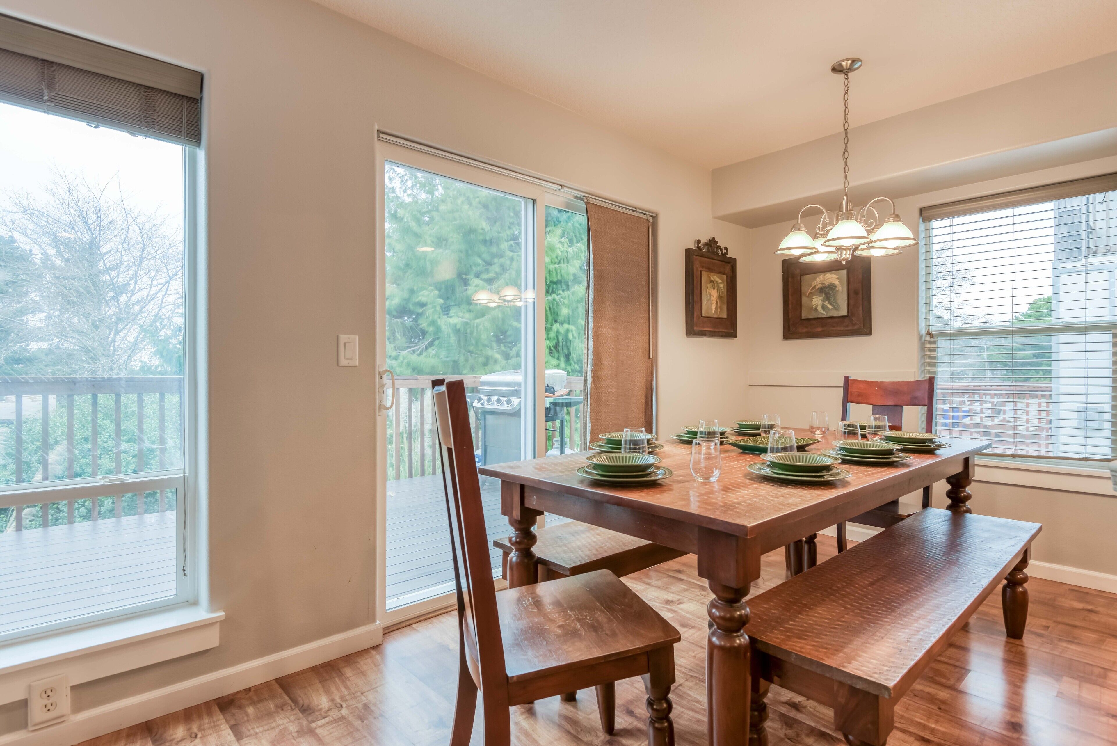 A dining area with a wooden table set for four, a bench, and a chandelier.