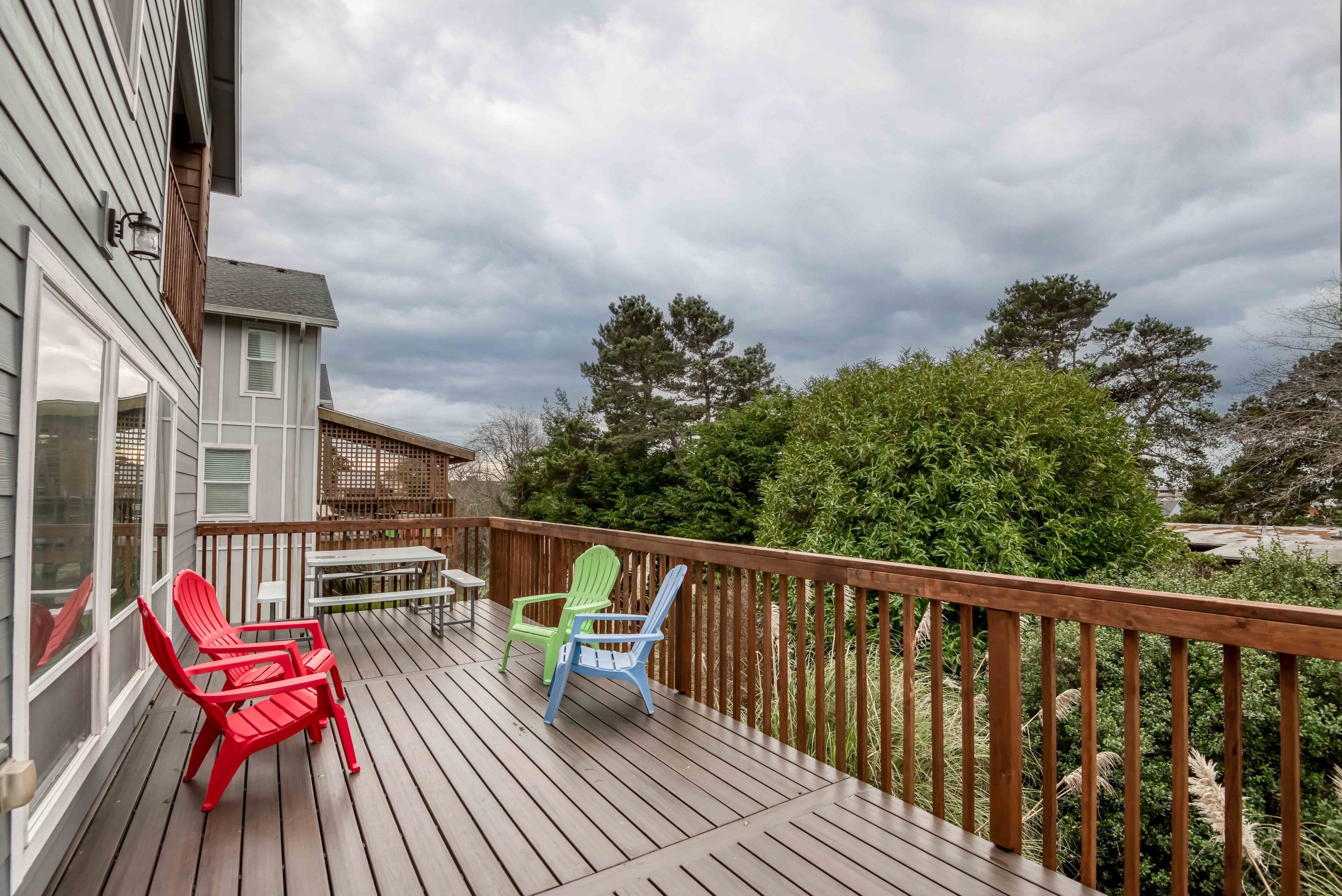 A wooden deck with outdoor seating and a view of a residential area.