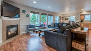 A spacious living room with a fireplace, comfortable seating, and large windows. - The perfect beach home for 10, 3 blocks to the beach, ocean views from the deck. (Lincoln City)