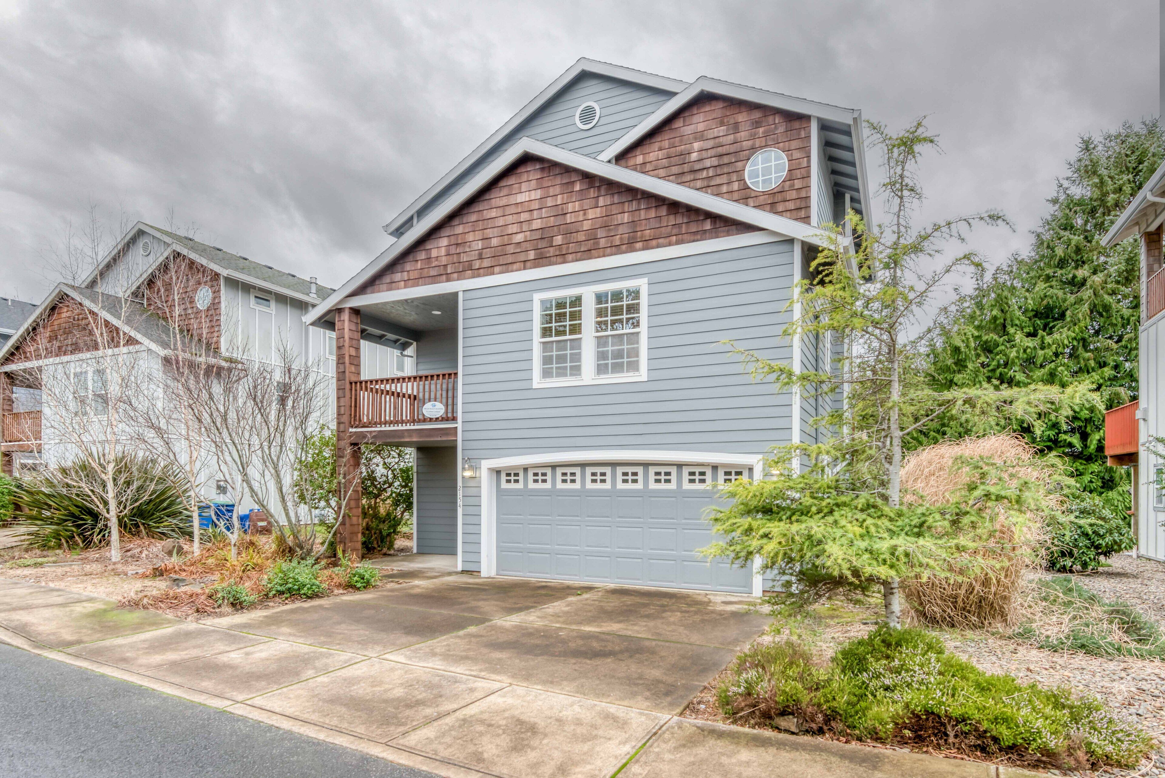 A two-story house with a garage, a balcony, and a well-maintained front yard with landscaping.