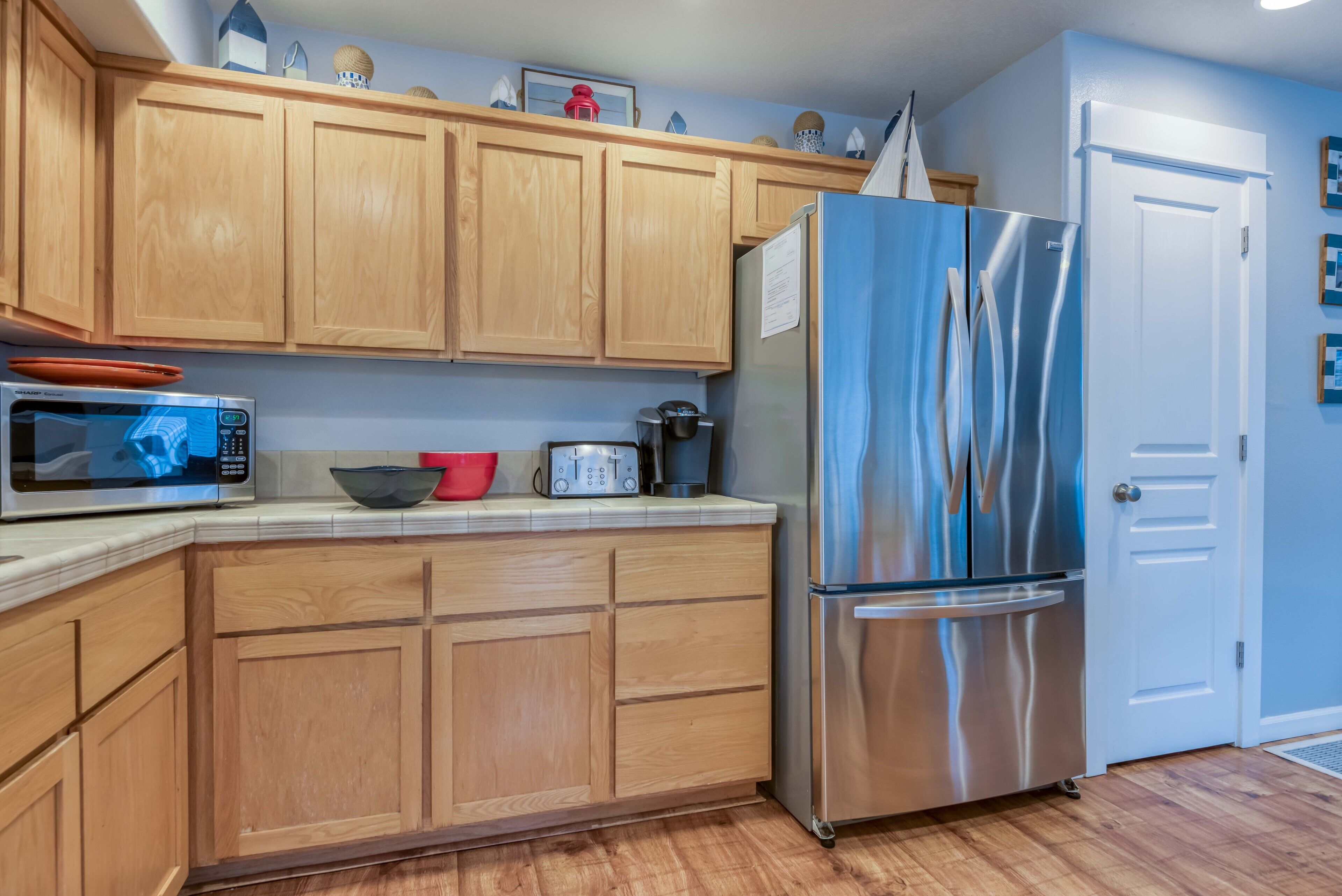 A kitchen with wooden cabinets, a stainless steel refrigerator, a microwave, and a toaster.