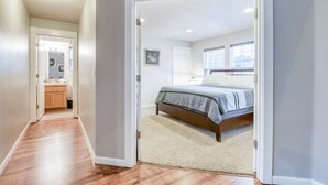 A bedroom with a bed, a window, and a door leading to a bathroom. - The perfect beach home for 10, 3 blocks to the beach, ocean views from the deck. (Lincoln City)