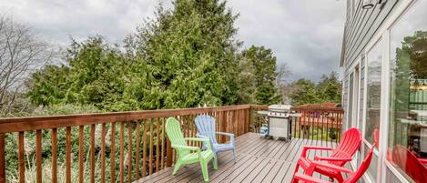 A wooden deck with outdoor seating and a view of a forest.