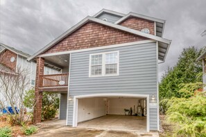 Ein zweigeschossiges Haus mit Garage, Balkon und überdachter Eingangszone.