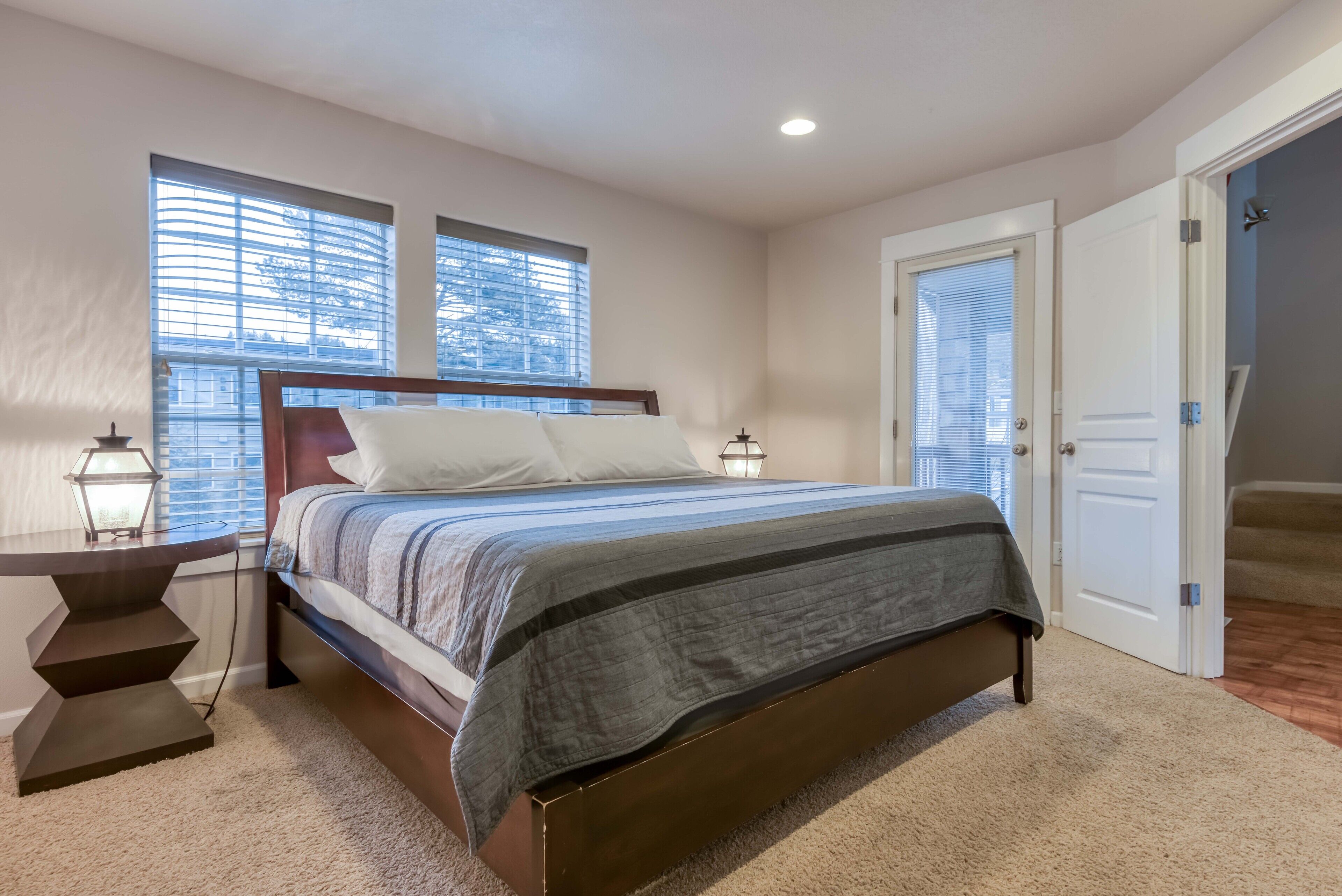 A bedroom with a bed, bedside tables, a lamp, and a window with blinds.