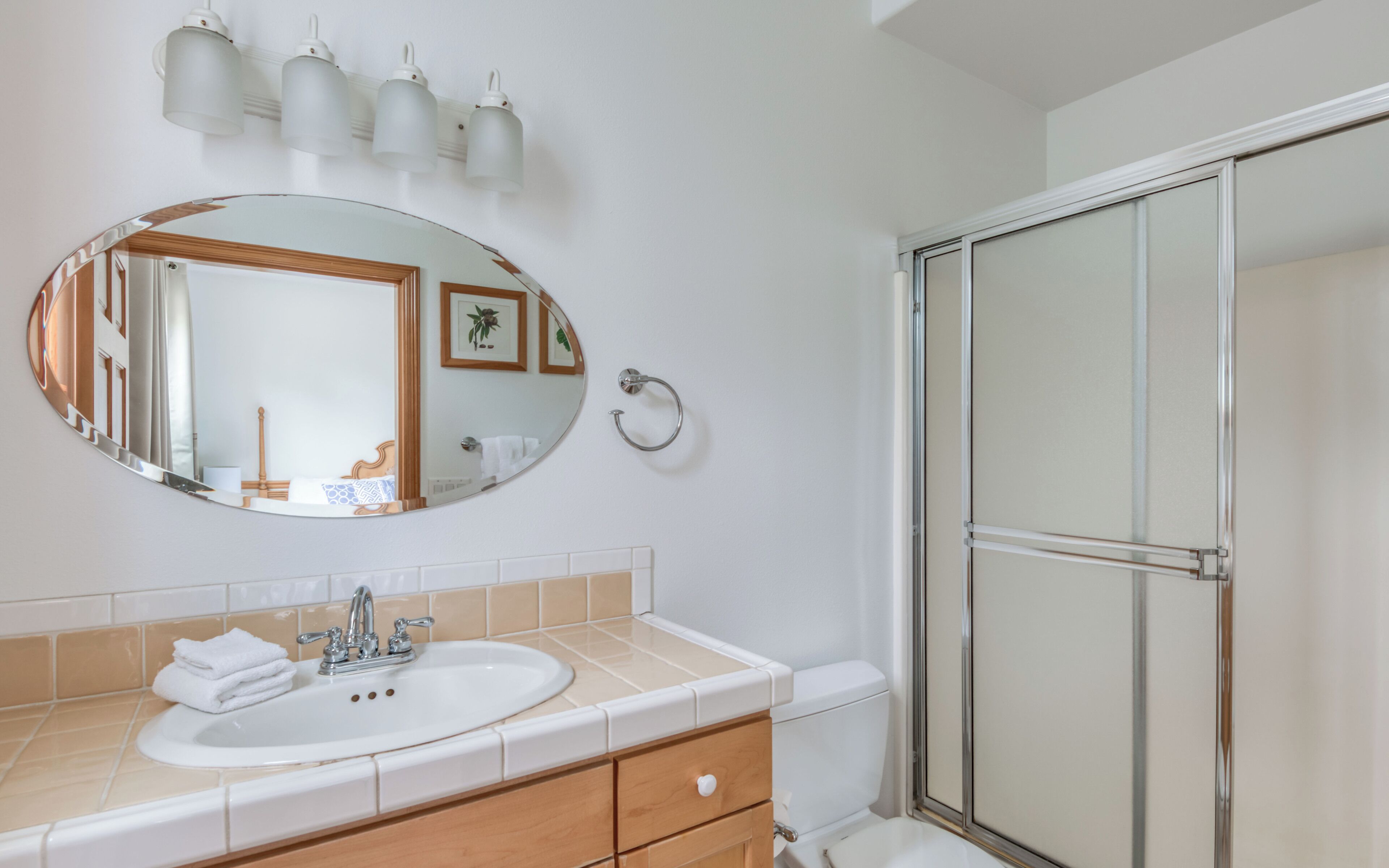 Un baño con un espejo redondo, un lavabo con grifo, un perchero para toallas y una zona de ducha.
