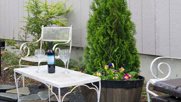 Een witte metalen tafel met twee wijnglazen en een fles wijn.