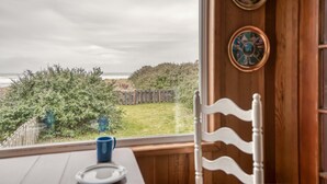 Ein Zimmer mit Meerblick, ein Holzstuhl, ein Tisch mit einer blauen Tasse und zwei dekorative Teller an der Wand.