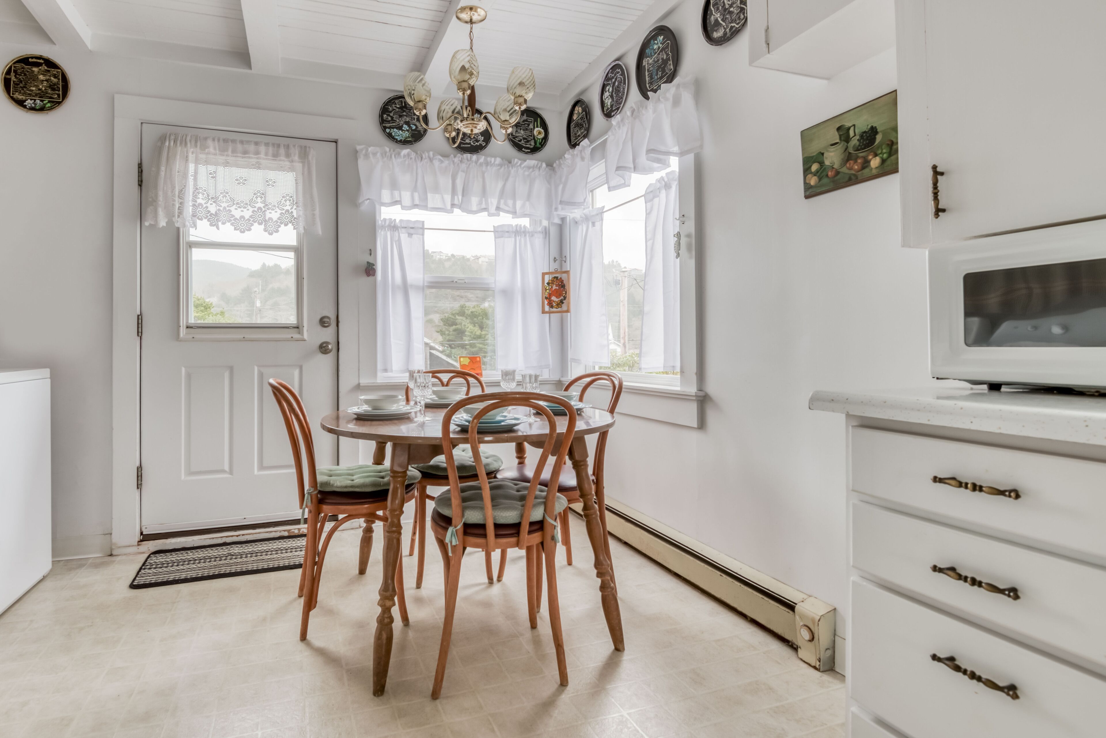 A dining area with a white door, a chandelier, and a table set for four.
