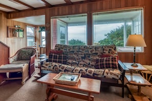 Relax in this inviting room with a sofa, wooden bench, and table, plus a view of the outdoors.