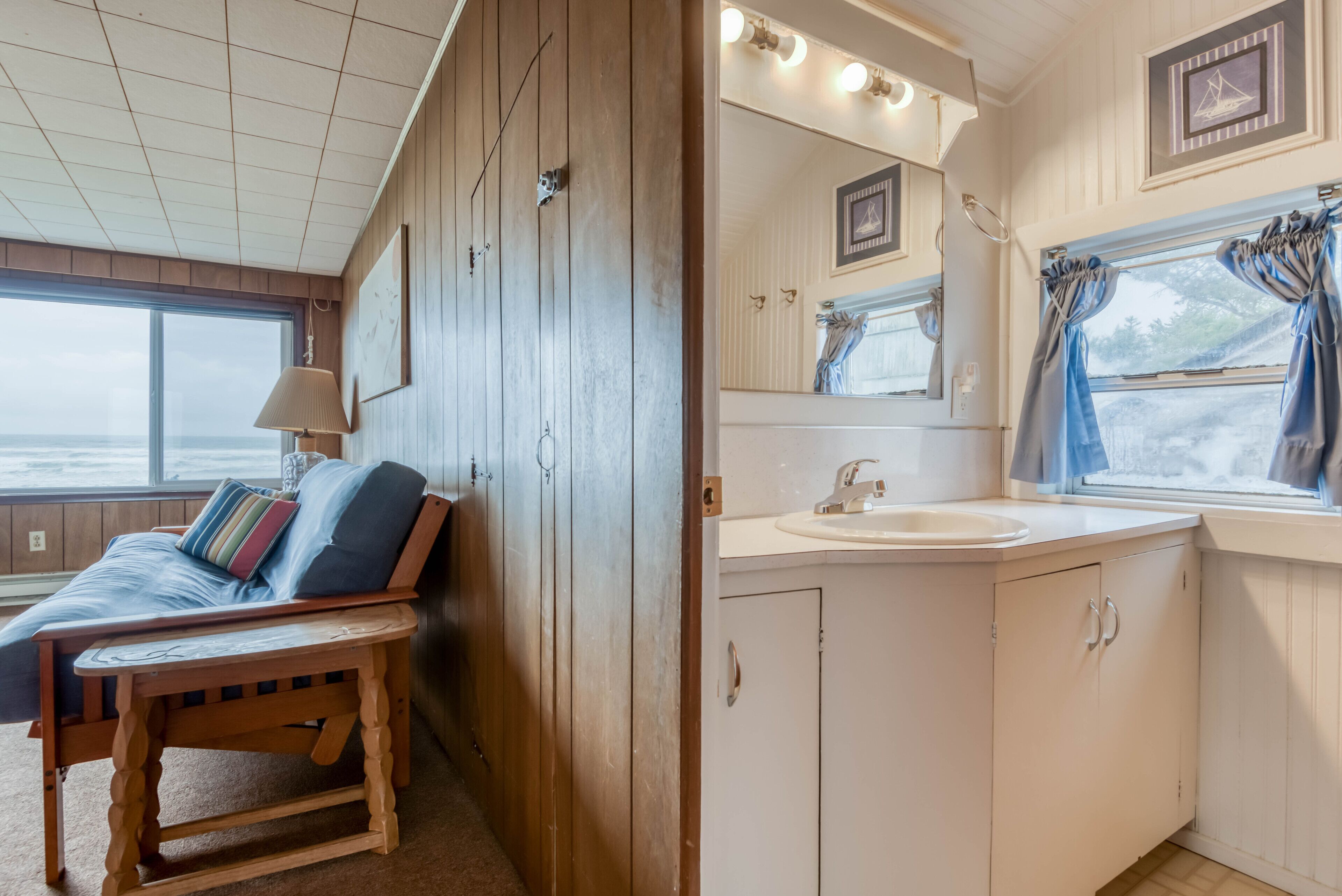 A cabin with a wooden bench, a small table, a white sink, and a mirror above it.