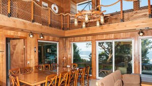 Een houten interieur met een eethoek, grote ramen en uitzicht op het landschap.