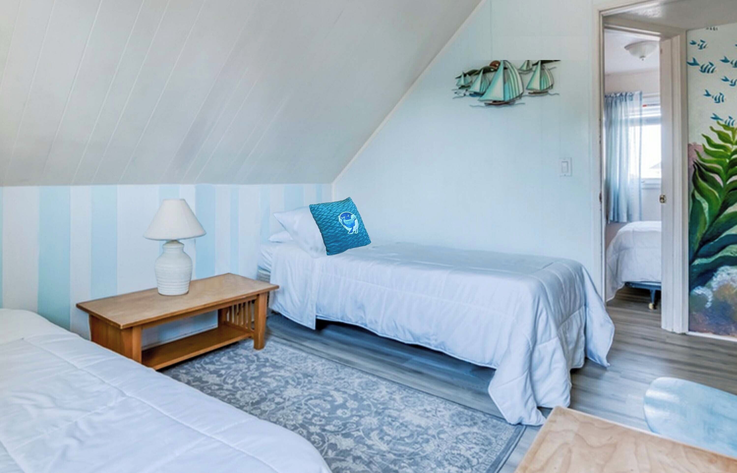 A bedroom with two beds, a nightstand, and a small table. There is a window with curtains and a door leading to another room.