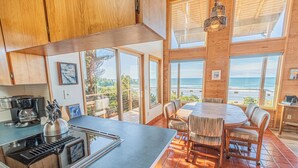 A modern kitchen with a large island, wooden cabinets, and a view of the ocean. - Oceanfront Home, Deck, High Windows with Amazing Views, Beach Access Nearby (Lincoln City)