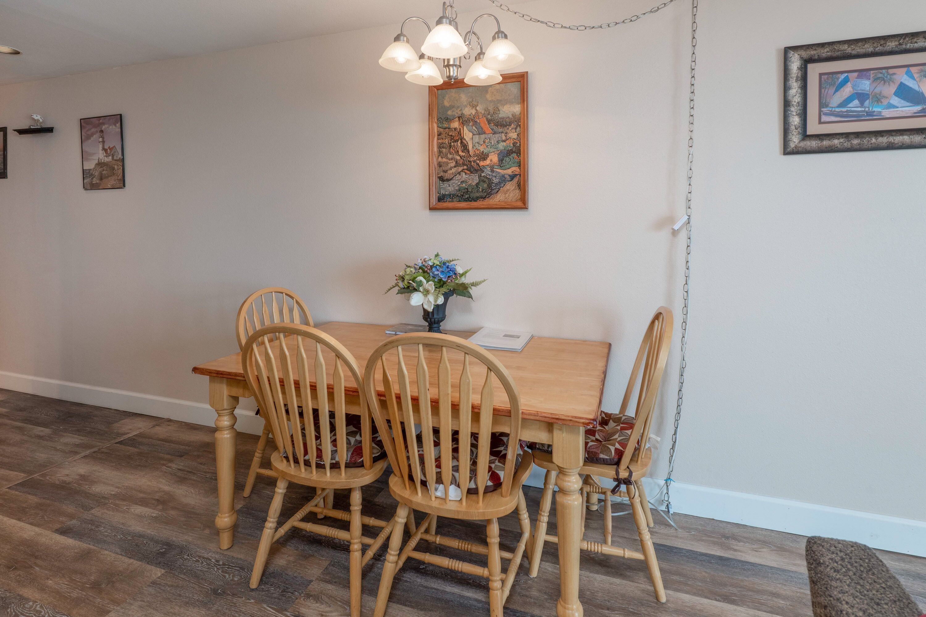 A dining area with a wooden table and chairs, a chandelier, and artwork on the walls.