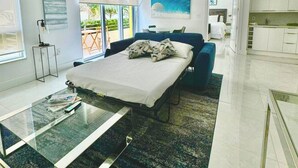 A modern bedroom with a bed, bedside table, and a view of the outdoors. - Private Condos at 101 Ocean by LMC (Miami Beach)