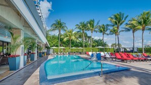 A swimming pool with lounge chairs and palm trees. - Private Condos at 101 Ocean by LMC (Miami Beach)