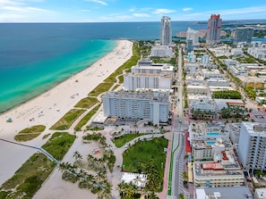An aerial view of a coastal city with a beach, high-rise buildings, and a clear blue sky. - Private Condos at 556 Ocean by LMC (Miami Beach)