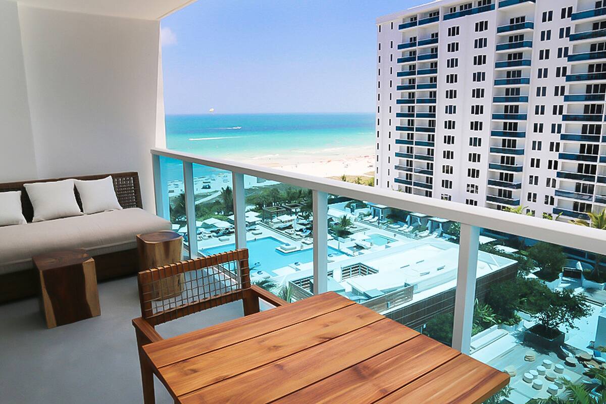 A balcony with a view of a beach and a pool area.
