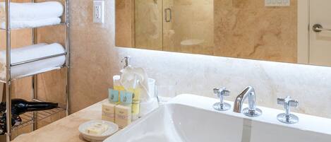 A bathroom with a large sink, a towel rack with folded towels, and toiletries on the counter.