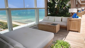 A balcony with a sofa, a wooden coffee table, and a small wooden cabinet with towels. - 1 Homes Vacation Rentals by LMC (Miami Beach)