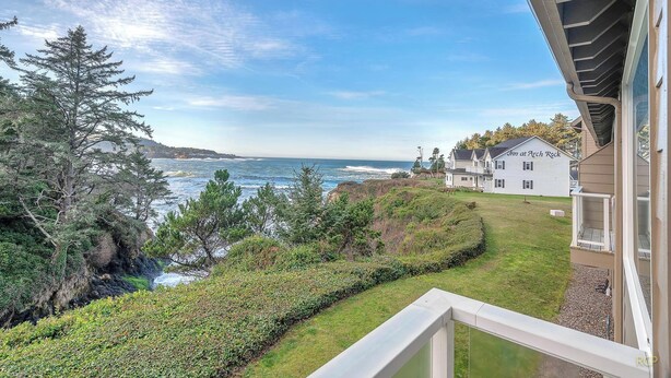 A coastal view with a house named "Inn at Arch Rock" and a grassy area with trees.