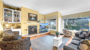 A cozy living room with a fireplace, a television, and a large window offering a scenic view.