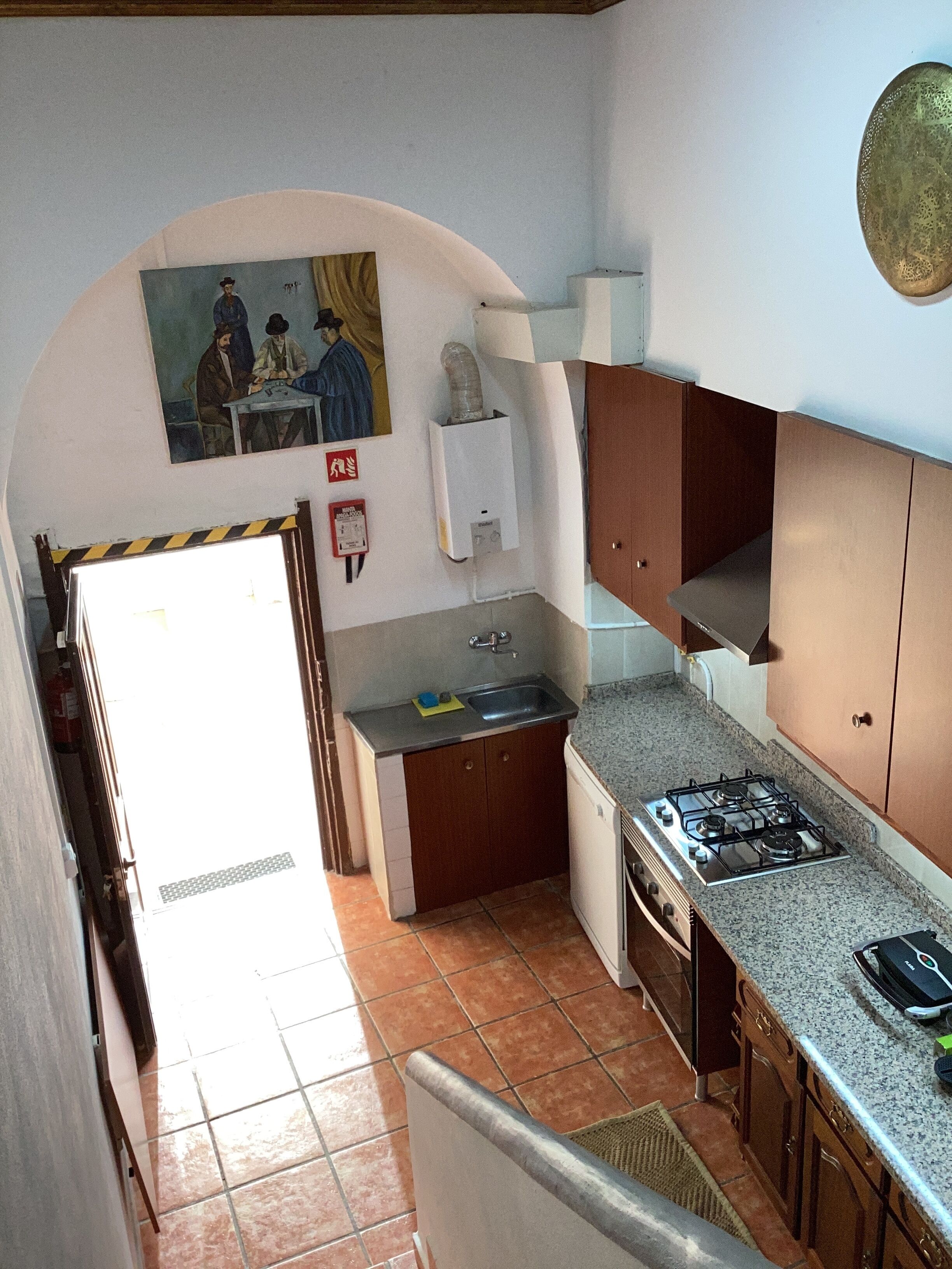 A compact kitchen with a gas stove, sink, and wooden cabinets.