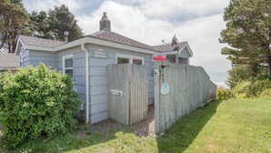 Ein kleines, eingeschossiges Gebäude mit der Aufschrift „BREEZE COTTAGE“, umzäumt von einem Holzzaun, und einem Schild mit der Beschriftung „LIEFERVERKEHR NUR.“