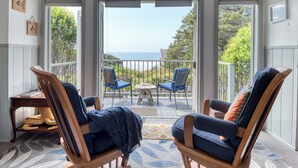 A balcony with two wooden chairs, a small table, and a view of the ocean.