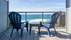 A wooden deck with two Adirondack chairs facing the ocean. - Take in panoramic views from the living room or deck at this oceanfront home (Lincoln City)