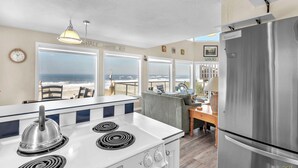 A kitchen with a view of the ocean, a stove, a refrigerator, and a dining area with a table and chairs. - Sweeping ocean views for your families getaway with easy access to great beaches (Lincoln City)